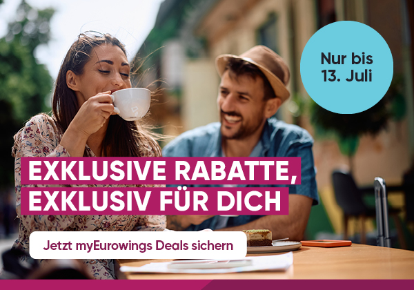 Eine Frau und ein Mann trinken gemeinsam Kaffee in einer europäischen Stadt. Jetzt exklusive Rabatte mit myEurowings sichern.