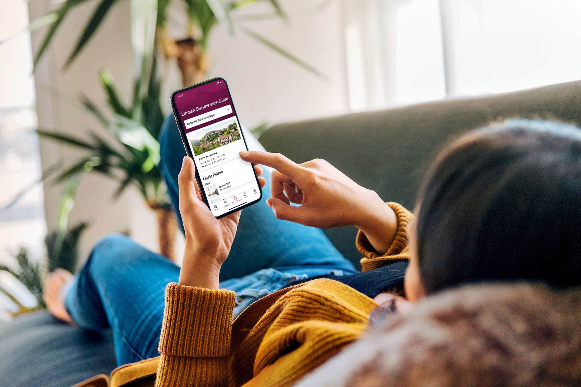 Eine Frau auf einem Sofa mit einem Smartphone in der Hand â€“ auf dem Display die Eurowings App.