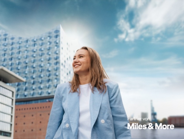 Frau steht vor der Elbphilharmonie in Hamburg. Jetzt Meilen sammeln.