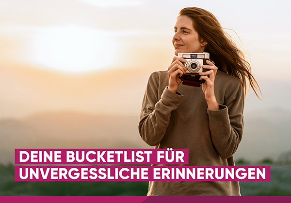 Eine Frau steht mit einer Analogkamera in der Natur.